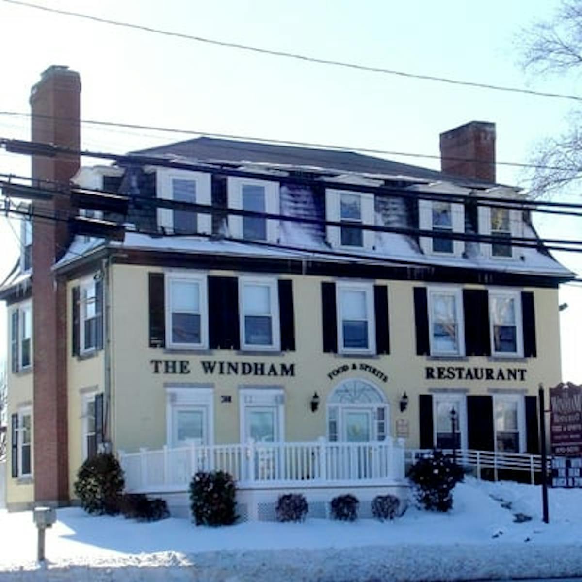 a house covered in snow in front of a building